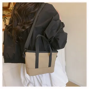 Détail d'un mini sac cabas kaki avec des sangles noires porté par une femme