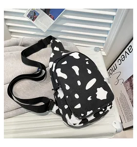 Detail of canvas crossbody bag with cow print pattern on suitcase and grey sweatshirt