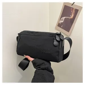 Vue détaillée du sac bandoulière en nylon noir avec logo brodé et textures fines