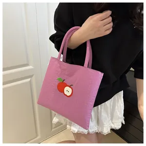 Close-up of a light purple canvas tote bag with detailed red apple embroidery detail
