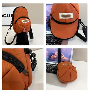 Detail view of orange baseball cap shaped nylon crossbody bag with zipper and logo