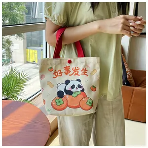 Detail of canvas gift bag featuring a cute panda on a persimmon with red handles