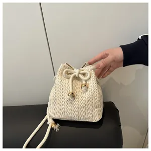 Detail of cream straw bucket bag featuring herringbone weave and gold bead drawstring