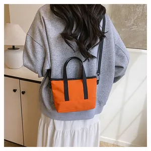 Vue arrière d'un mannequin portant un mini sac cabas orange avec bandoulière noire