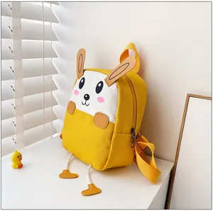 Détail du sac à dos en toile jaune avec oreilles de lapin et visage de dessin animé
