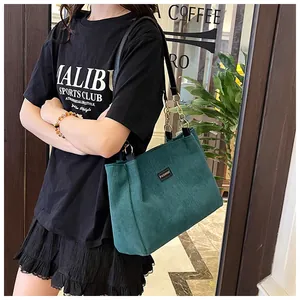 Detail of dark green corduroy tote bag featuring fashion label and gold chain strap