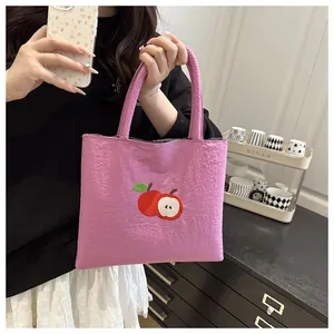 Detail of purple canvas tote bag featuring a high-quality red apple embroidery design