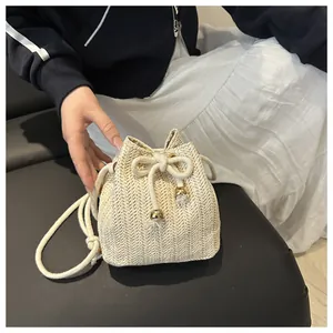 Close-up of beige woven straw bucket bag with herringbone pattern and gold beads