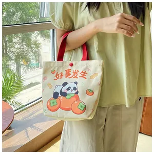 Detail of canvas bag with cute panda illustration and red ribbon handle in a lifestyle setting