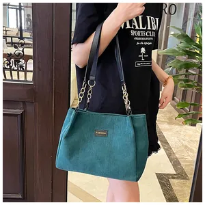 Detail of green corduroy tote bag with black leather and gold chain shoulder straps