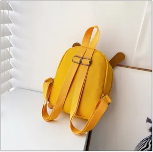 Détail d'un sac à dos en toile jaune avec bretelles réglables et décor d'oreilles mignon