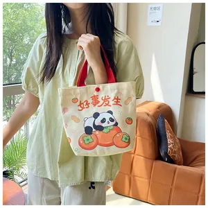 Close-up of canvas tote bag featuring panda illustration and red snap button closure