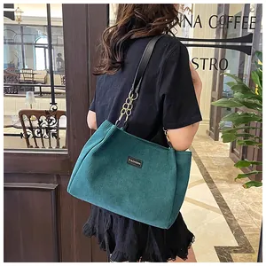 Detailed texture of dark green corduroy tote bag with golden chain and fashion label