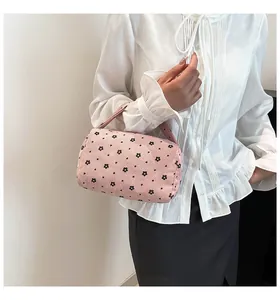 Detail of pink floral corduroy cylinder bag held by model wearing a white shirt