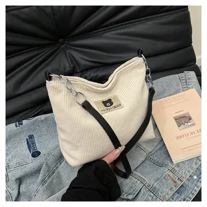 Detail of corduroy tote bag featuring bear leather patch and metal chain strap
