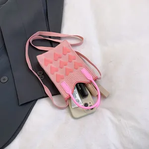 Pink knitted mini handbag with heart pattern showing capacity for phone and lipstick