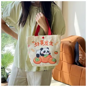 Detail of canvas tote bag with panda print, red handles and button closure
