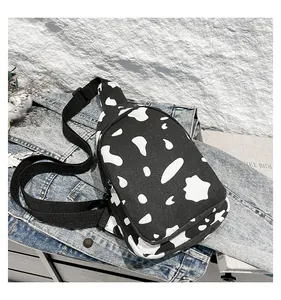 Detail of canvas chest bag with cow pattern on denim jacket and textured background