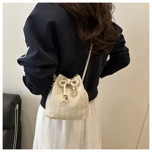 Detail of woven straw bucket bag featuring drawstring closure with gold bead accents