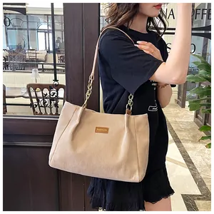 Detail of corduroy tote bag featuring leather 'FASHION' label and gold chain strap