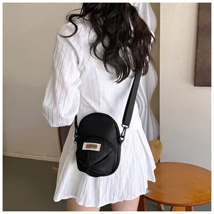 Detail of black mini nylon crossbody bag with scalloped pleats shown on a model