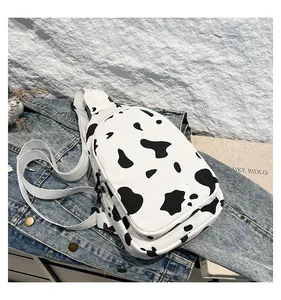 Detail of cow print canvas chest bag with white adjustable strap on denim background