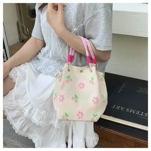 Close-up of knit tote bag with pink flower patterns and woven rope handle details