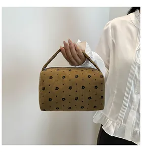 Detailed texture of brown corduroy makeup bag with floral print and zipper closure