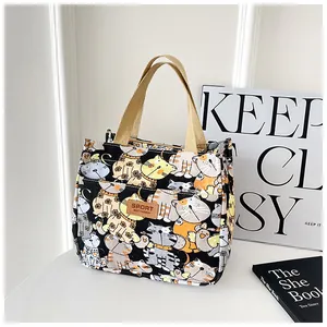 Detail van canvas lunchtas met kattenprint en bruin lederen merklabel op tas