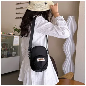 Detail of a black nylon crossbody bag with white tag shown in a cozy cafe setting