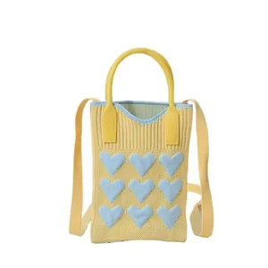 Mini knit crossbody bag in yellow featuring blue heart patterns and top handle
