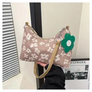 Close-up of khaki floral canvas tote bag featuring green flower pendant and strap detail