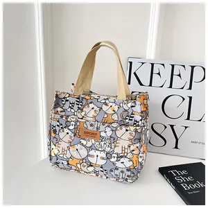 Detailopname van canvas handtas met cartoon katpatronen en een lederen merklabel