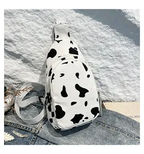 Detailed view of the cow print canvas chest bag featuring dual zipper pockets and strap