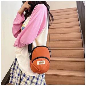 Detail of vibrant orange nylon crossbody bag with zipper pocket and adjustable strap