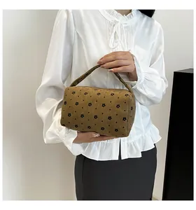 Close-up of corduroy storage bag with black floral print held by a model in a white shirt