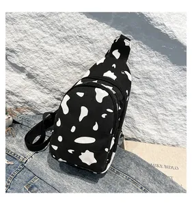 Detail showing the cow print canvas chest bag with adjustable strap on a denim backdrop
