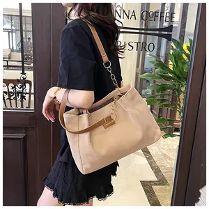 Detail of beige corduroy tote bag showing metal chain strap and fashion label on shoulder