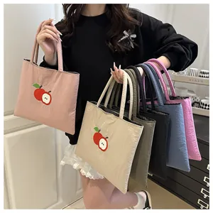 Close-up of apple embroidery detail and diverse color options for large canvas tote bags
