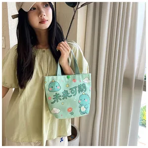 Detail of light green canvas tote bag with cartoon dinosaur print and snap closure