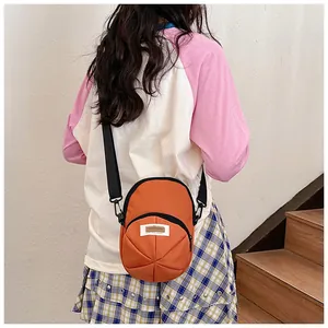 Back view of model wearing an orange canvas crossbody bag on a wooden staircase