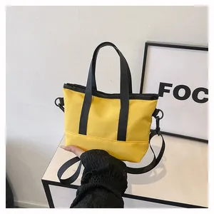 Sac bandoulière en toile jaune avec poignée noire, détails de couture et bandoulière