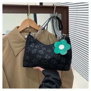 Detail of black floral textured hobo bag with silver chain and green flower charm