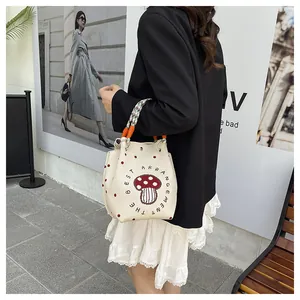 Close-up of knit tote bag with mushroom print and colorful braided handles in street style