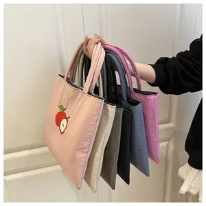 Quilted tote bags in various colors featuring apple embroidery and padded handles