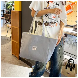 Detail of light blue corduroy tote bag featuring striped texture and minimalist label