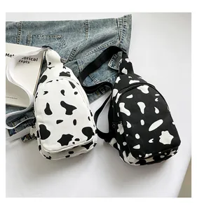 Detail of canvas crossbody bag with cow print pattern and double zipper compartments