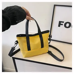 Détail du cabas en toile jaune avec poignées noires et bandoulière amovible