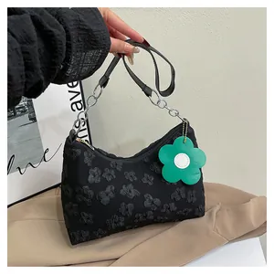 Detail of black floral jacquard shoulder bag with silver chain and green flower charm