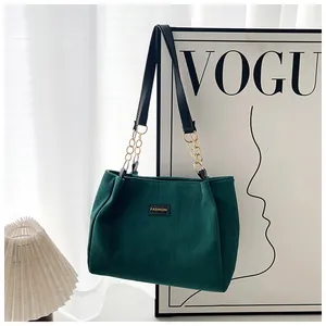 Detail of dark green corduroy tote bag with golden metal chain strap and leather label